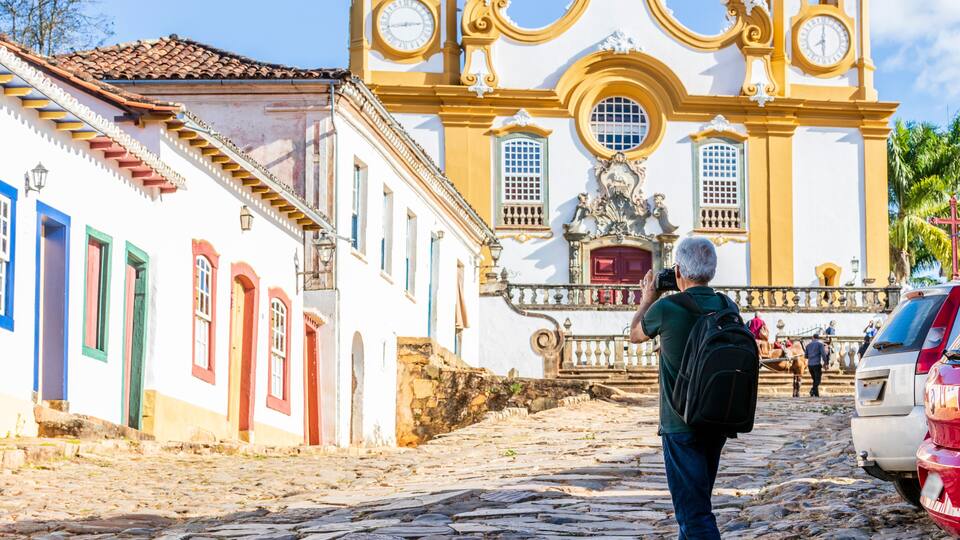 A cobblestone street leading to a historic church with a bell tower and a statue.