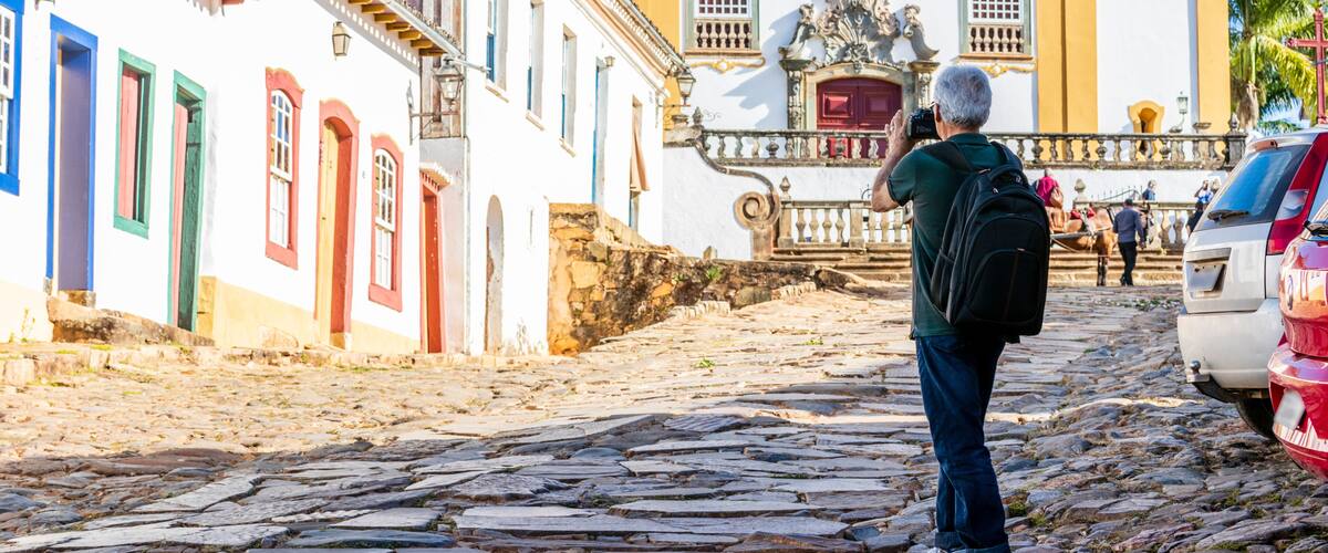 A cobblestone street leading to a historic church with a bell tower and a statue.