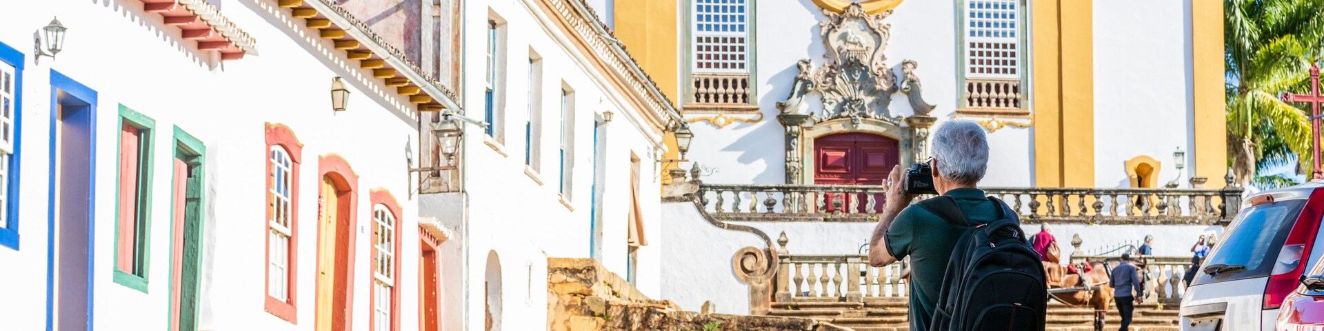 A cobblestone street leading to a historic church with a bell tower and a statue.