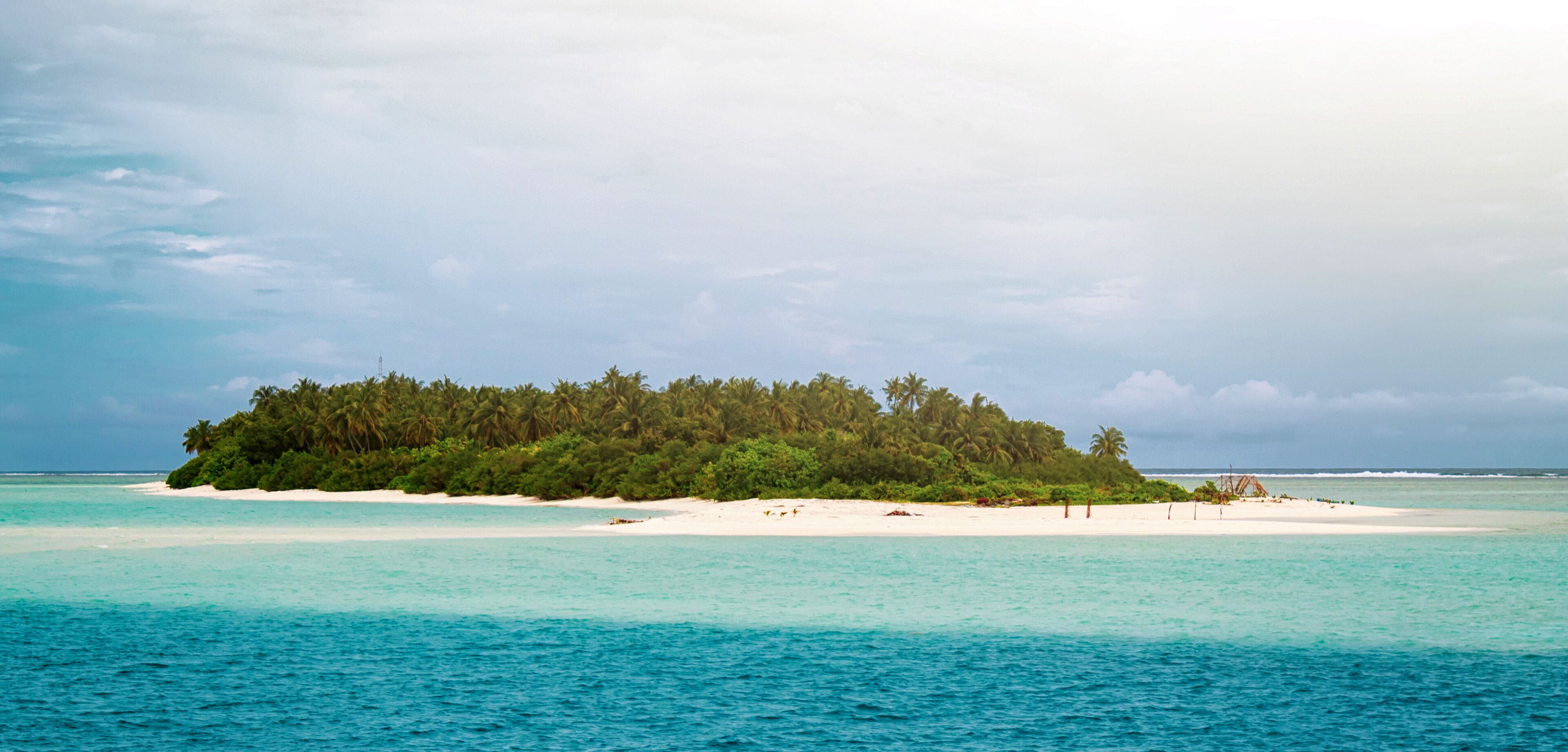A small island with dense green vegetation and white sandy beaches surrounded by turquoise waters.