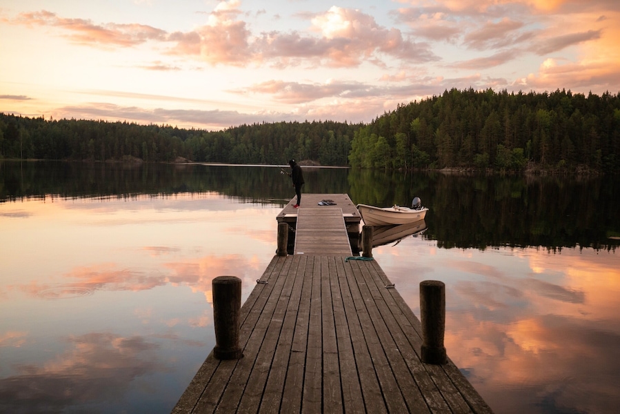 A wooden pier extending into a calm lake with a forested shoreline.