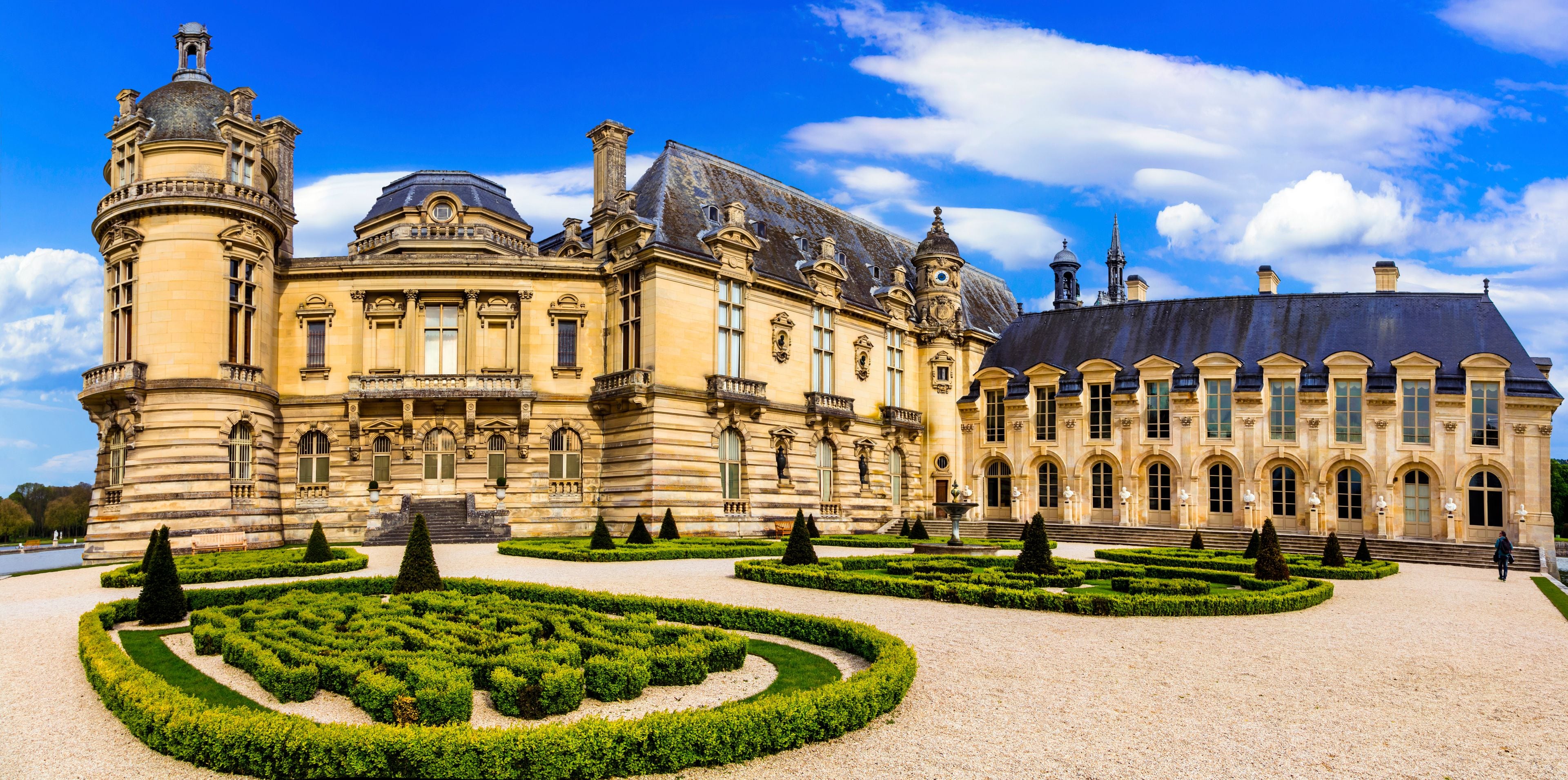 Chateau de Chantilly panoramic view with ornamental garden in France. Beautiful scenic French royal palace castle architecture with manicured formal hedges and no people. World Print