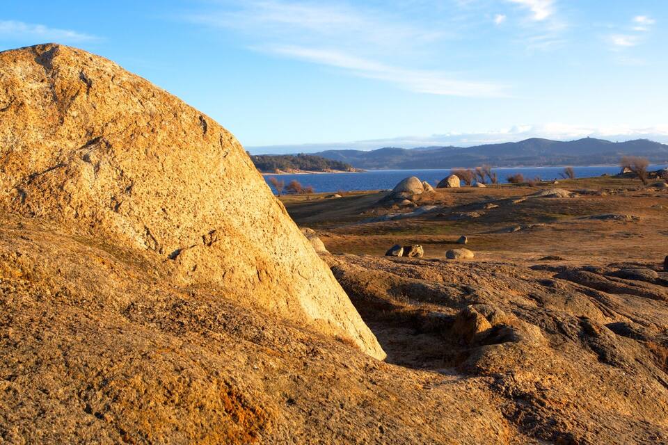 A large rock formation, a lake, and distant mountains.