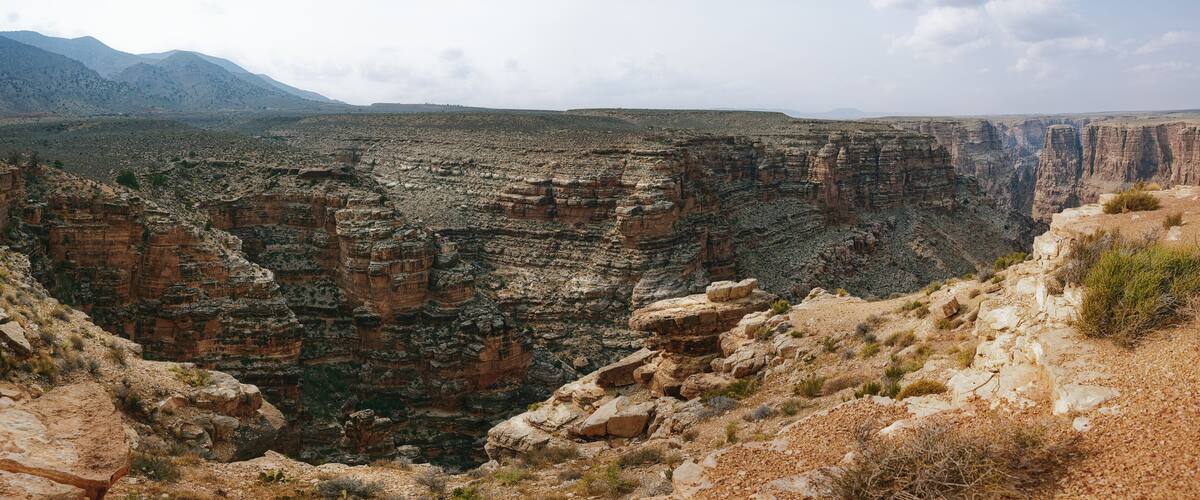 A canyon with layered rock formations and distant mountains.