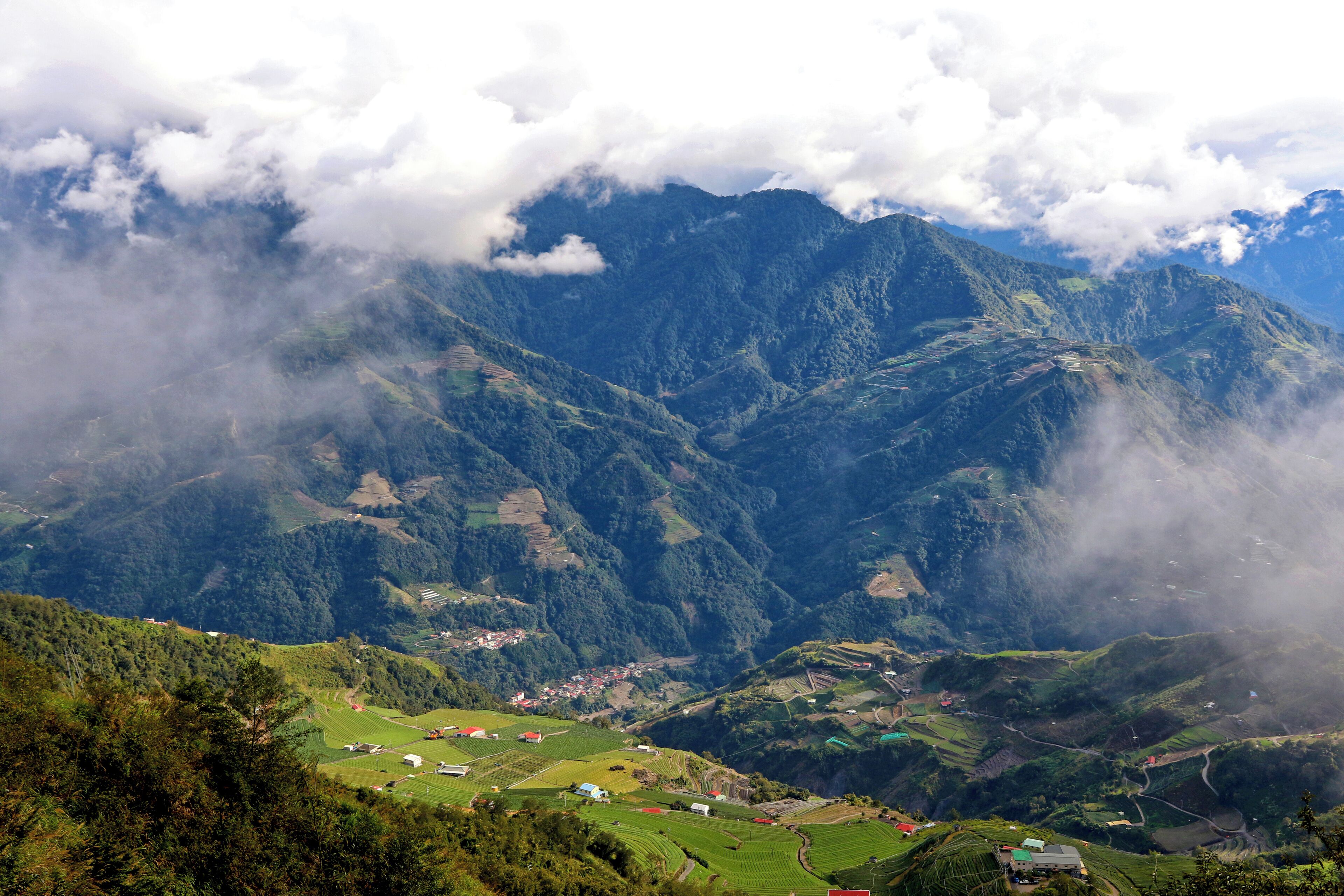 A mountainous landscape with terraced fields and scattered buildings.