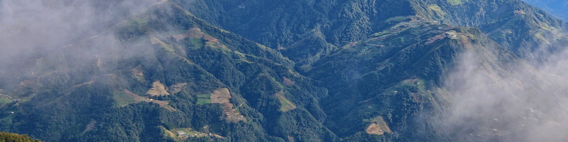 Un paisaje montañoso con campos escalonados y edificios dispersos.