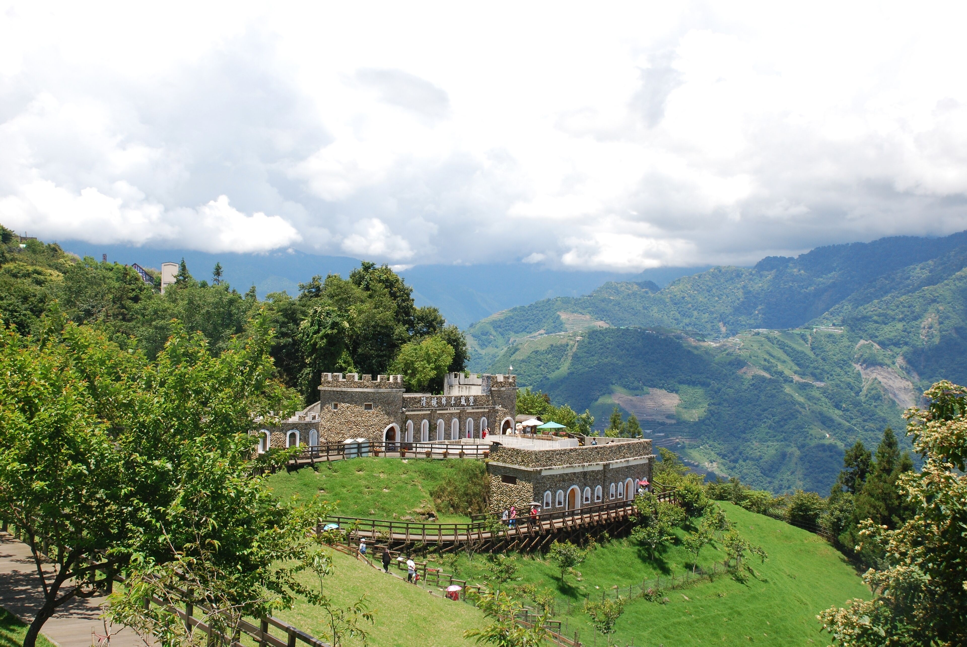 Un castillo histórico en una colina verde y exuberante, con una vista panorámica de las montañas circundantes.