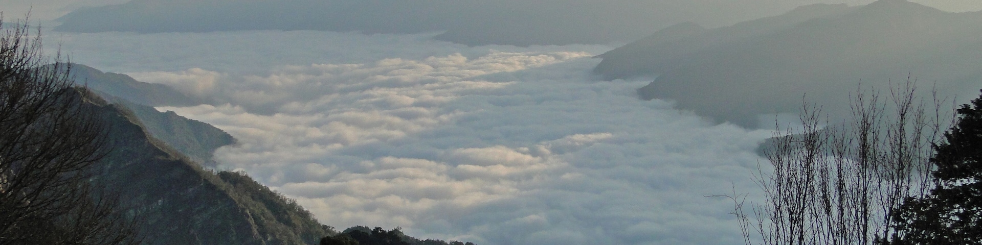 Un paisaje montañoso con un valle cubierto de nubes.
