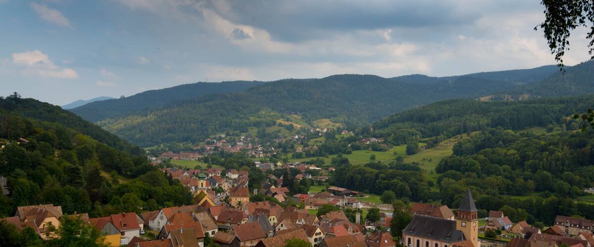 A town nestled in a valley surrounded by hills, with a prominent church tower and a mix of traditional houses.