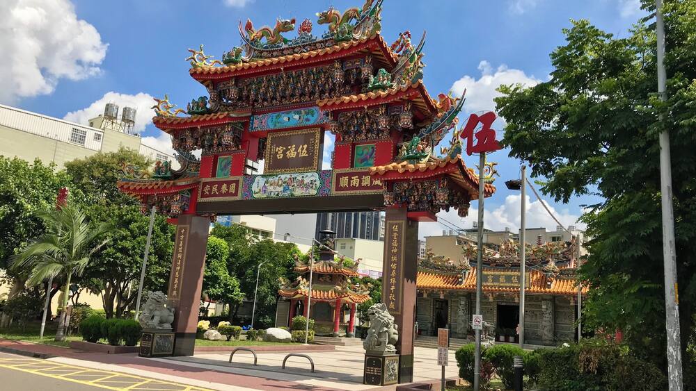 A traditional Chinese gate with intricate designs and a dragon figure on top.