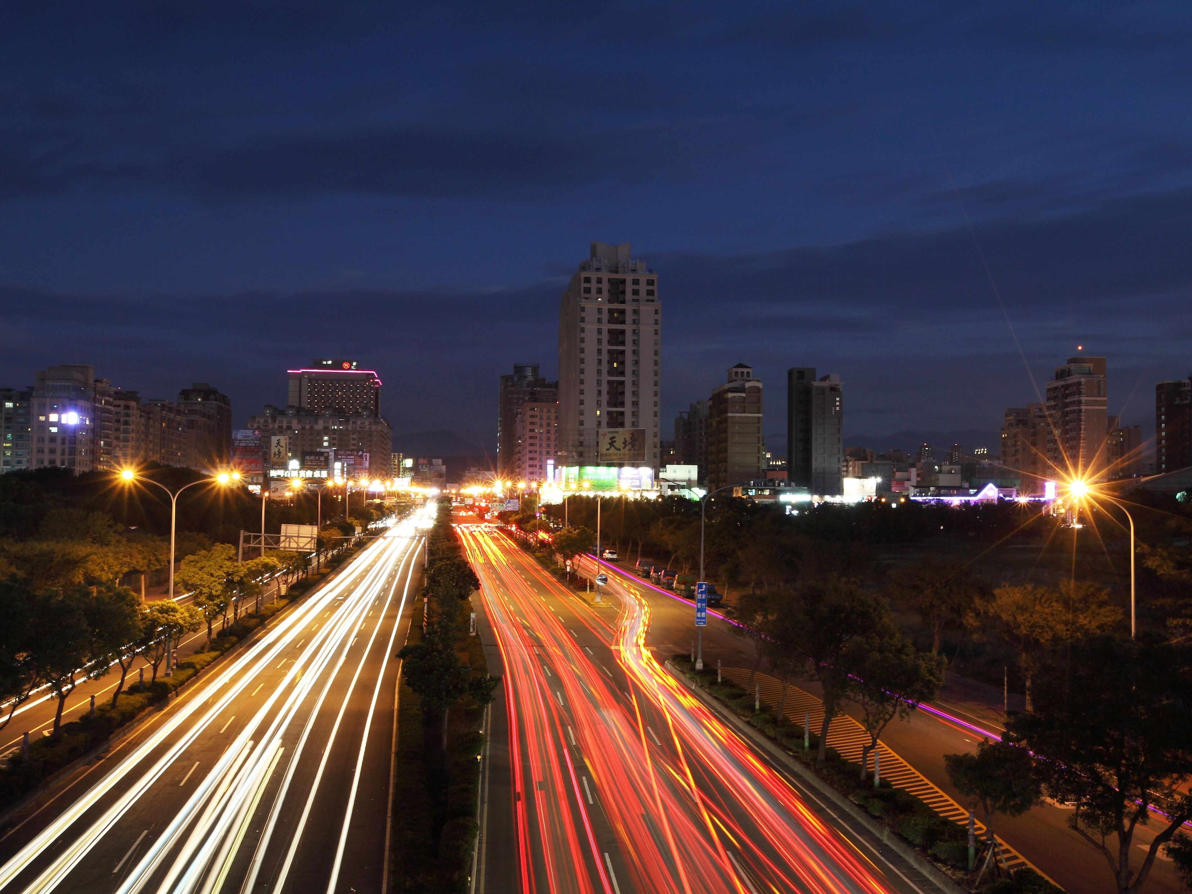 A nighttime cityscape with illuminated buildings and a busy multi-lane highway.