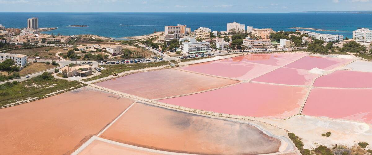 An aerial view of a coastal town with salt flats and the sea.