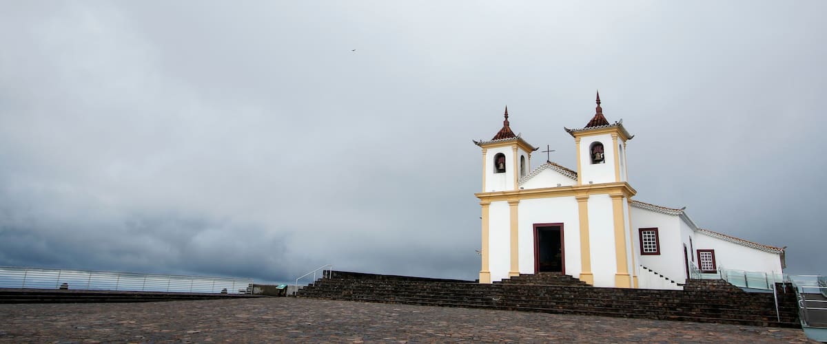 A white church with two bell towers and a stone staircase leading up to it.