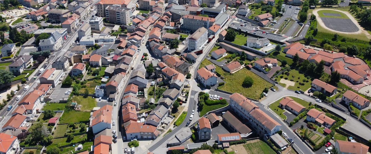 An aerial view of a town with red-roofed buildings, green fields, and a large church.