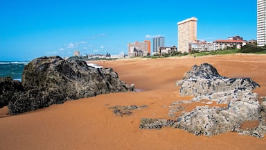 Une plage de sable avec de gros rochers et des vagues de l’océan.