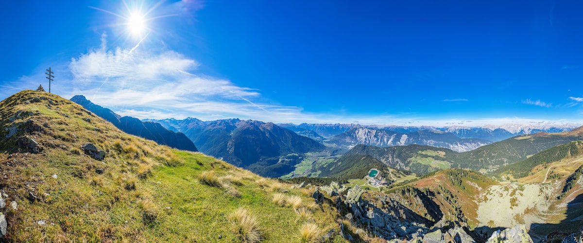 A mountainous landscape with a clear sky, a prominent peak, and a valley below.