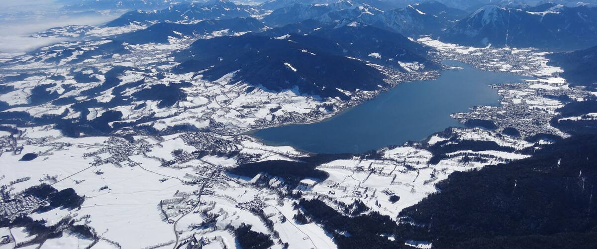 A snow-covered mountainous landscape with a lake and a town.