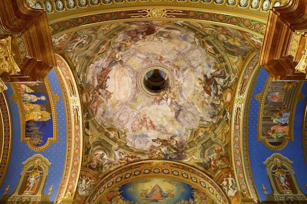 Eine aufwendig dekorierte Decke mit filigranen Fresken und goldenen Akzenten.