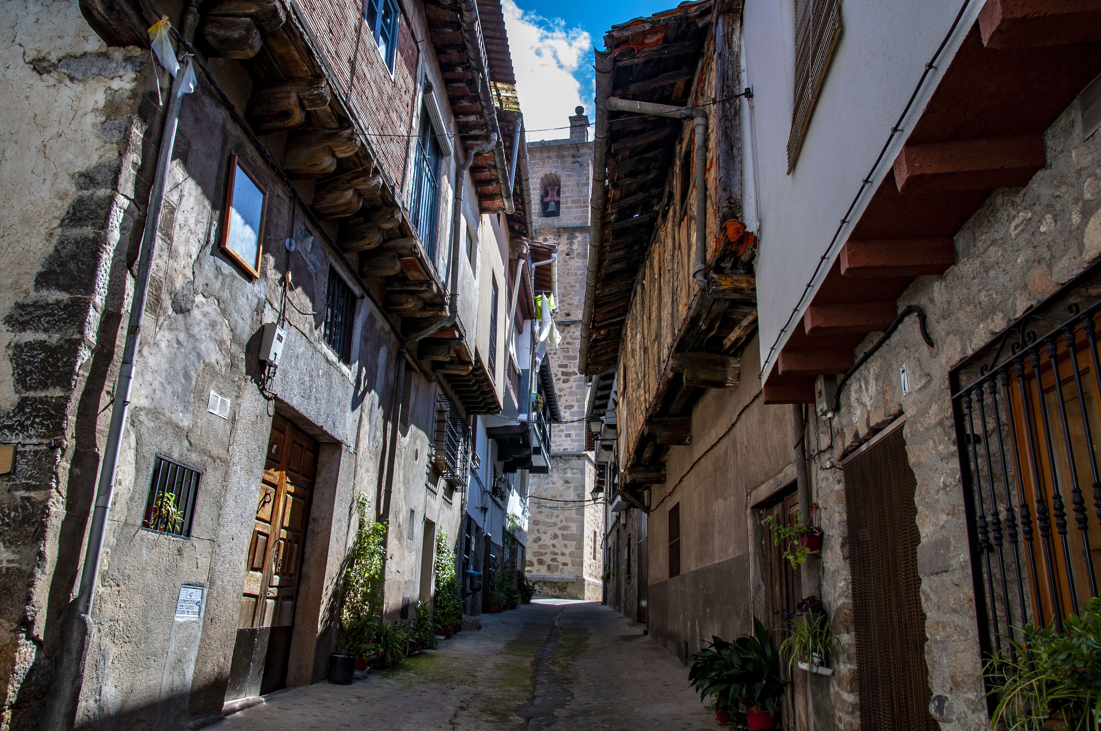 A narrow cobblestone alley flanked by historic buildings with stone facades and wooden shutters.