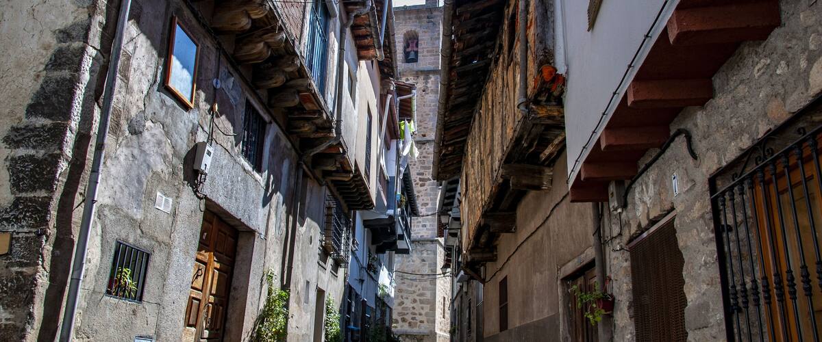 A narrow cobblestone alley flanked by historic buildings with stone facades and wooden shutters.