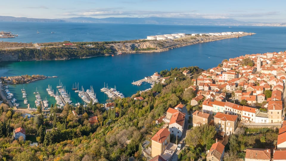 A coastal town with a marina, boats, and historic buildings.