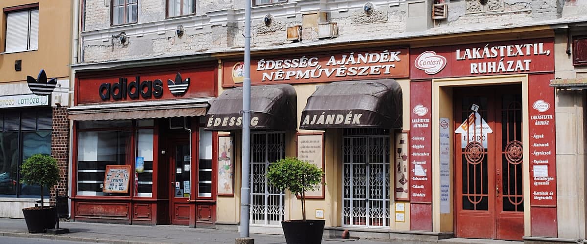 A street with a building featuring an Adidas store and a pharmacy.