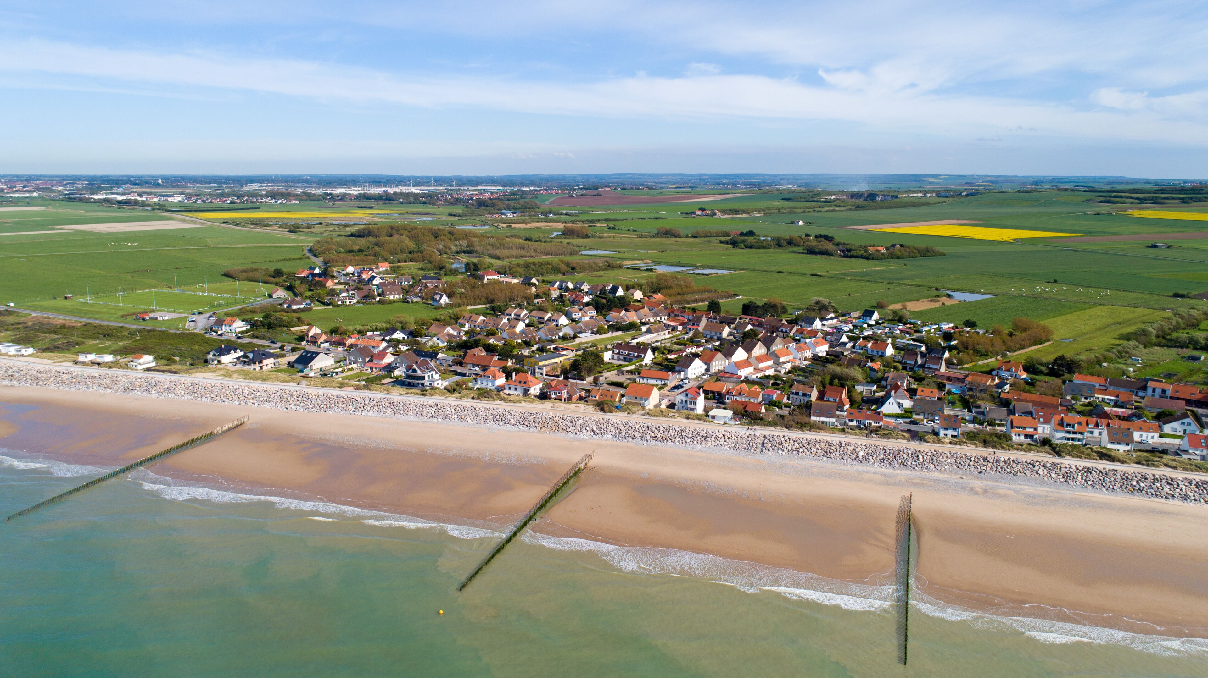 A coastal village with houses, a beach, and fields.