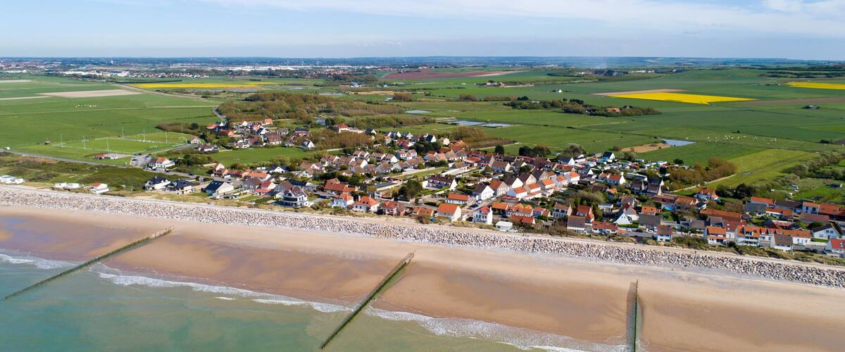 A coastal village with houses, a beach, and fields.