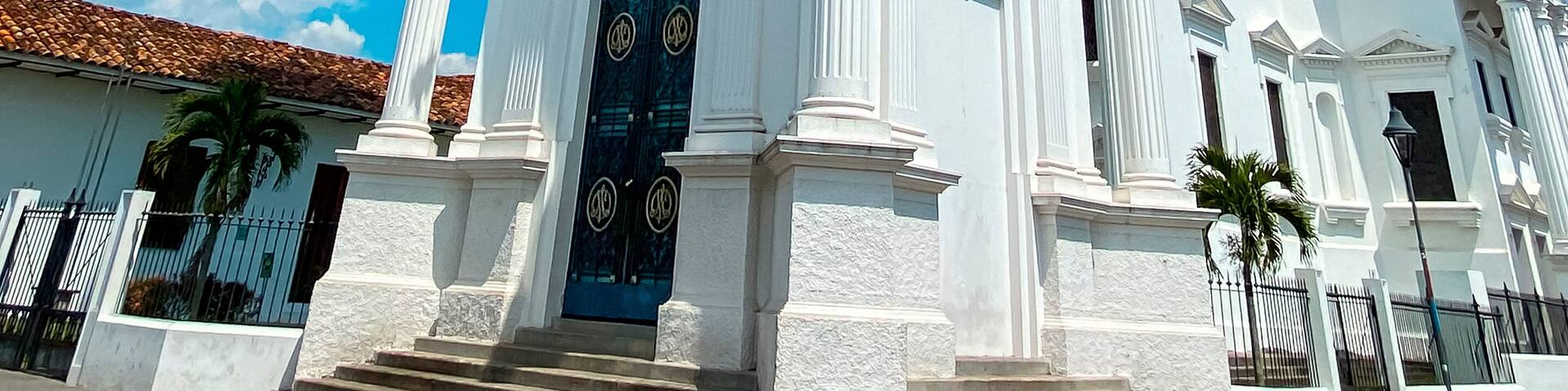A white church with a clock tower, large windows, and a dome.