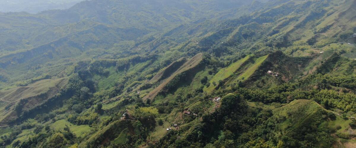A mountainous landscape with lush greenery and scattered small buildings.