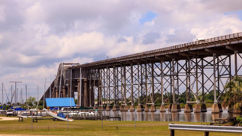 A large steel bridge over water with boats docked nearby.