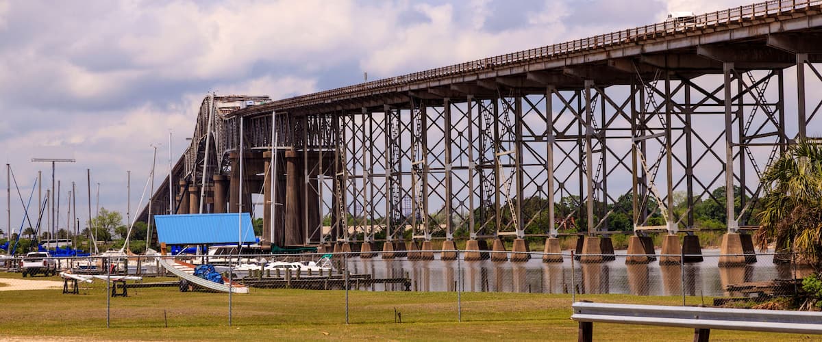 A large steel bridge over water with boats docked nearby.