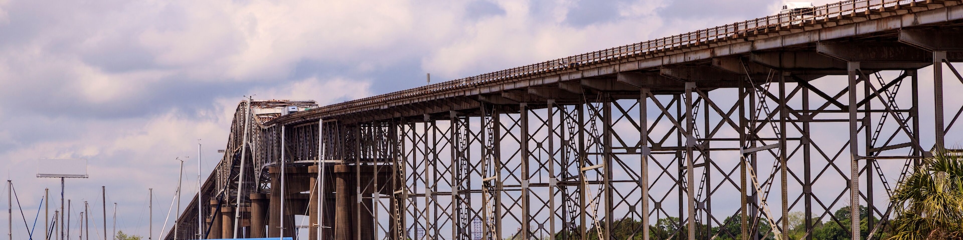 A large steel bridge over water with boats docked nearby.