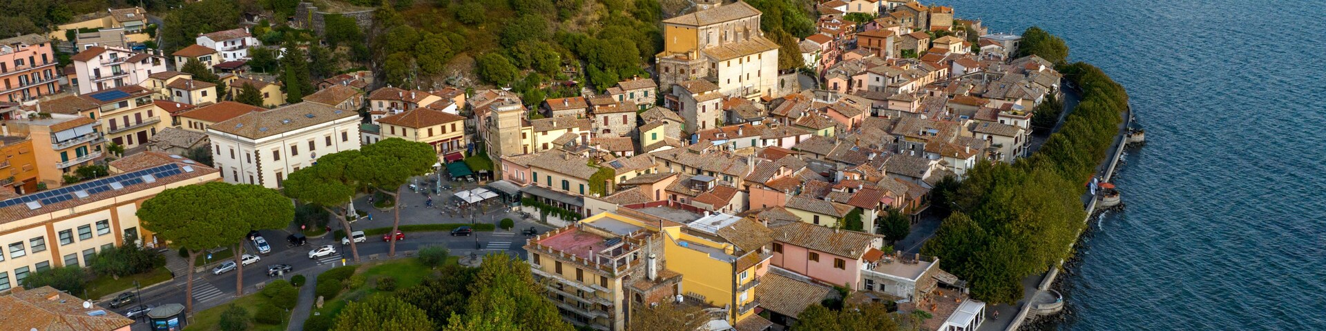 A coastal town with historic architecture, a prominent castle on a hill, and a calm lake.