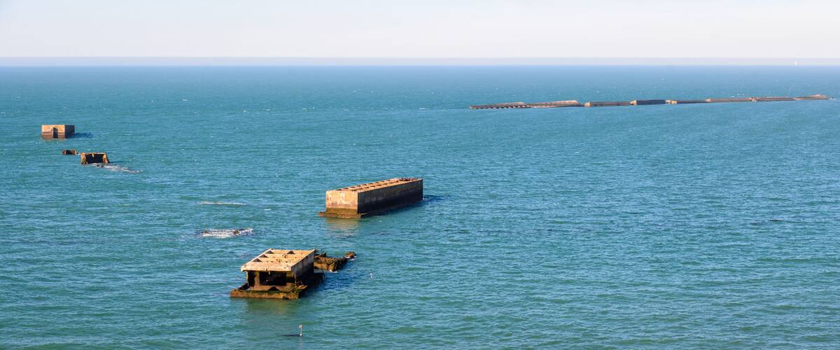 A calm sea with several concrete structures floating on the water.