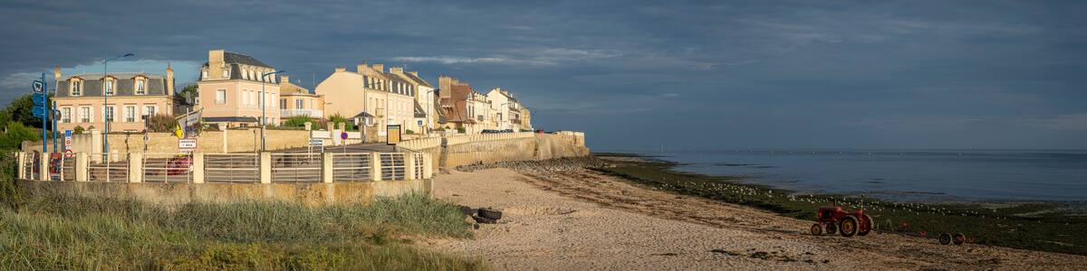 Langrune-Sur-Mer, France - 08 07 2025: Panoramic view of the jetty, the beach and the sea with a sunny cloudy sky
