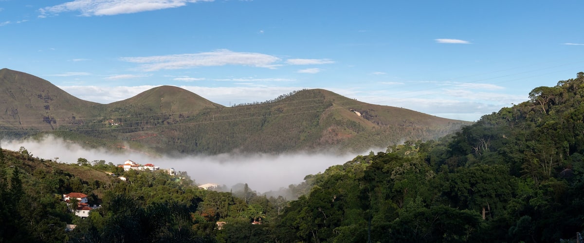 A valley with a lake surrounded by mountains and dense forest.