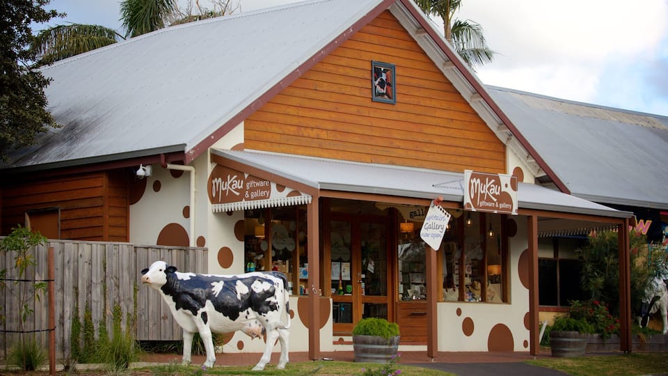 A building with a cow statue in front, wooden siding, and a sign that reads "Mukau giftware & gallery".