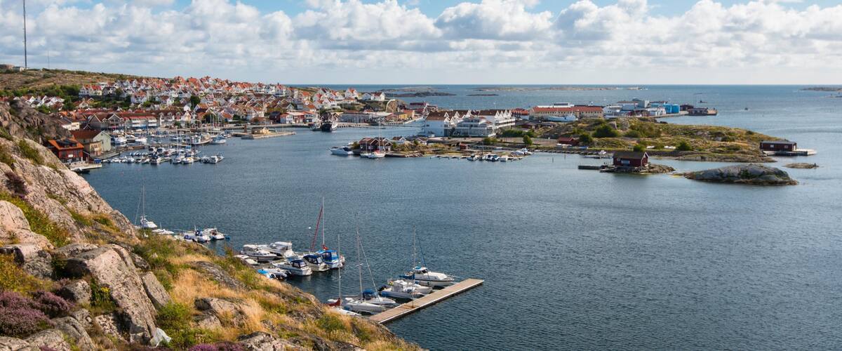A coastal town with a marina, houses, and rocky terrain.