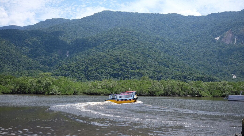 A cruise boat touring the small river close to Bertioga Brazil on a sunny day before the hills with green woods, wild nature life