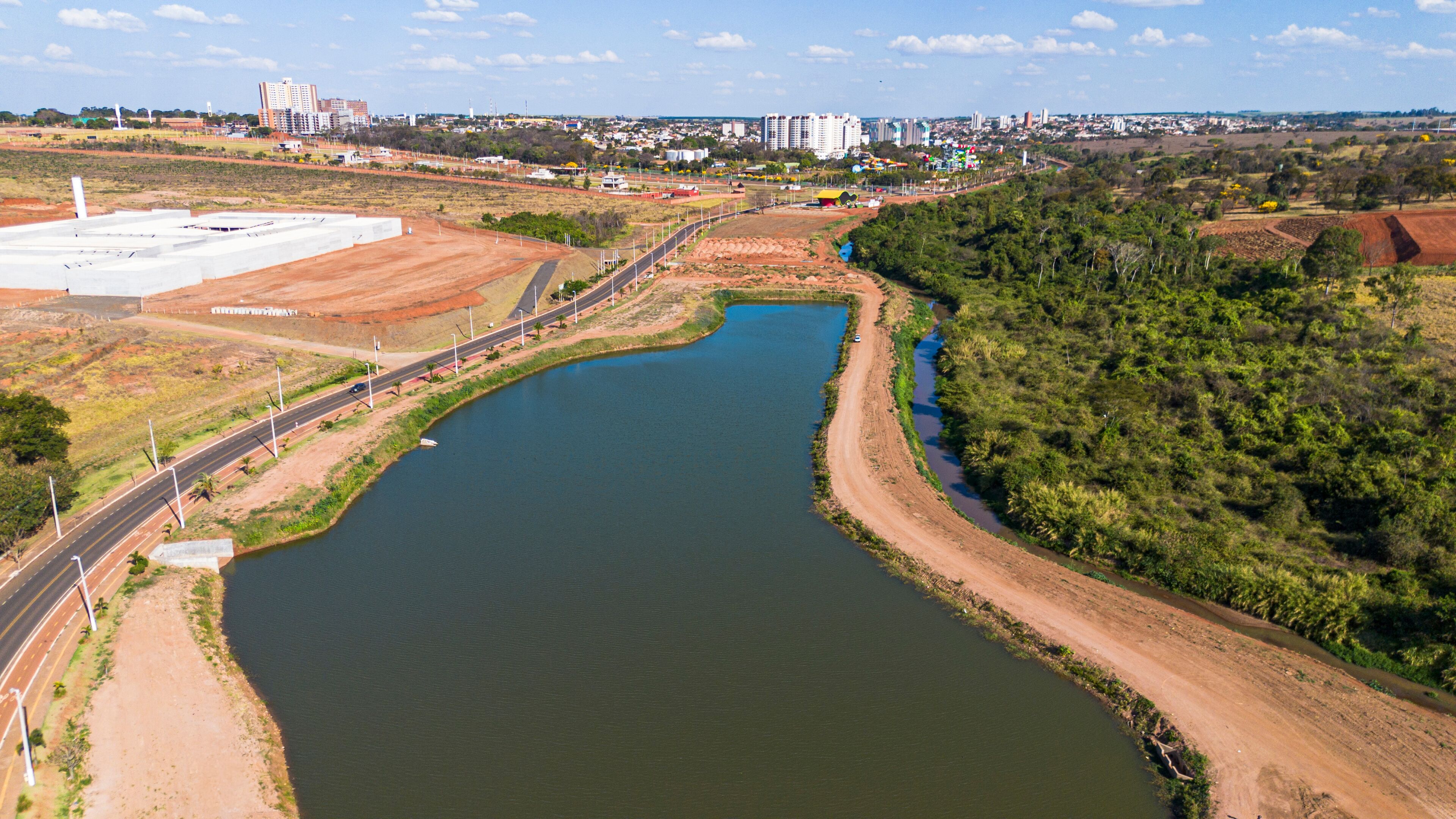 A river curving through a landscape with a road on one side and a large industrial area on the other.