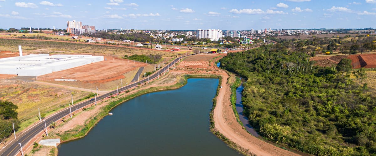 A river curving through a landscape with a road on one side and a large industrial area on the other.