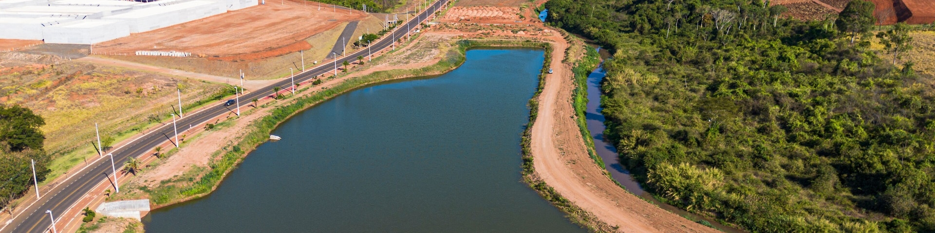 A river curving through a landscape with a road on one side and a large industrial area on the other.