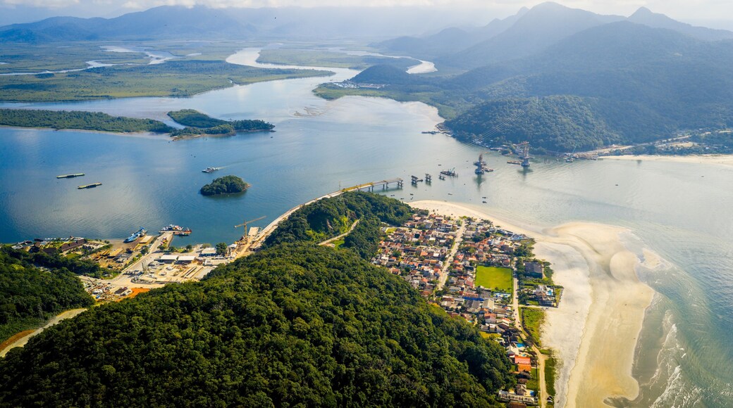 Aerial view of Caieiras Beach with ferry crossing and Guaratuba-Matinhos bridge construction surrounded by lush landscape.