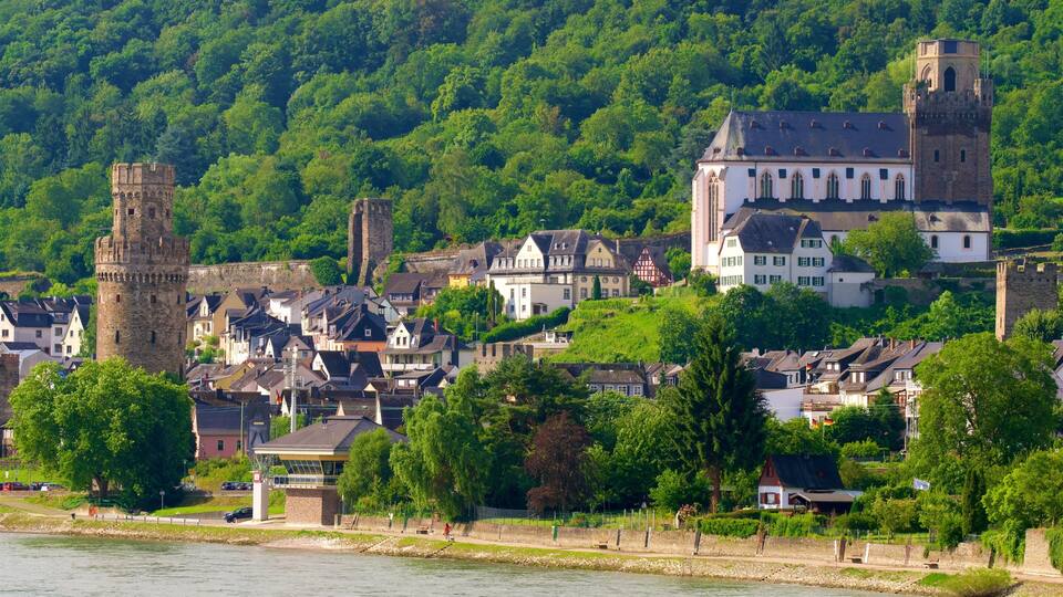 A historic town with a prominent tower, lush green hills, and a river.