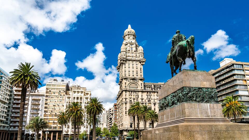 A cityscape with a prominent tower and a statue of a figure on horseback.