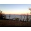 A calm lake at sunset with trees in the foreground and a clear sky.