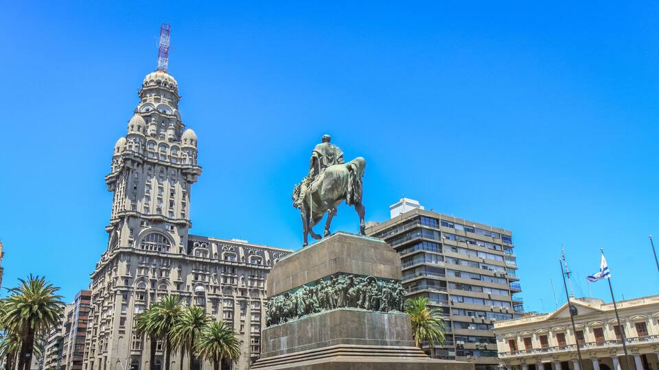 A statue of a man on horseback, a large ornate building, and palm trees.