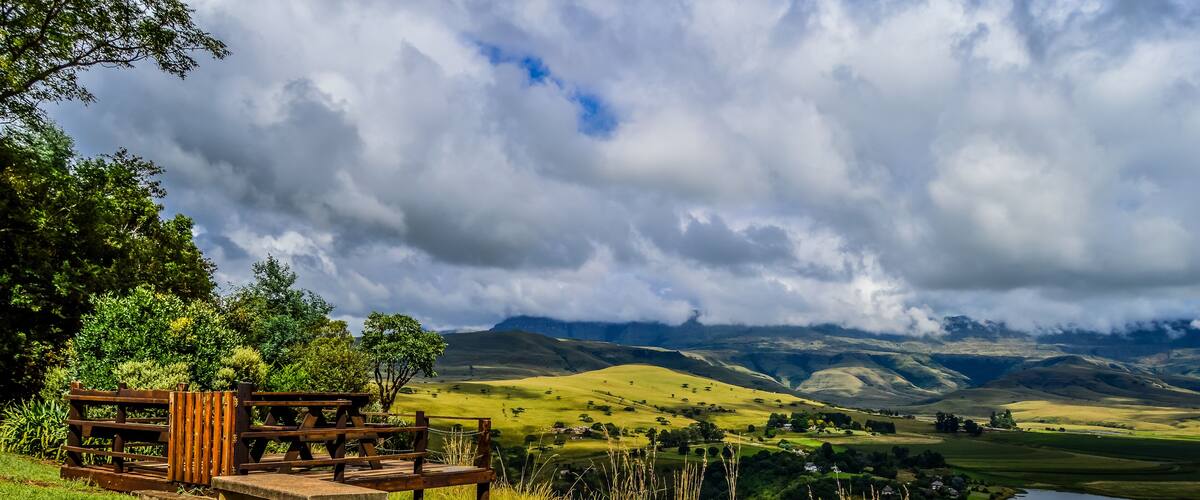 A picnic area with a bench and table overlooking a lake and rolling hills.