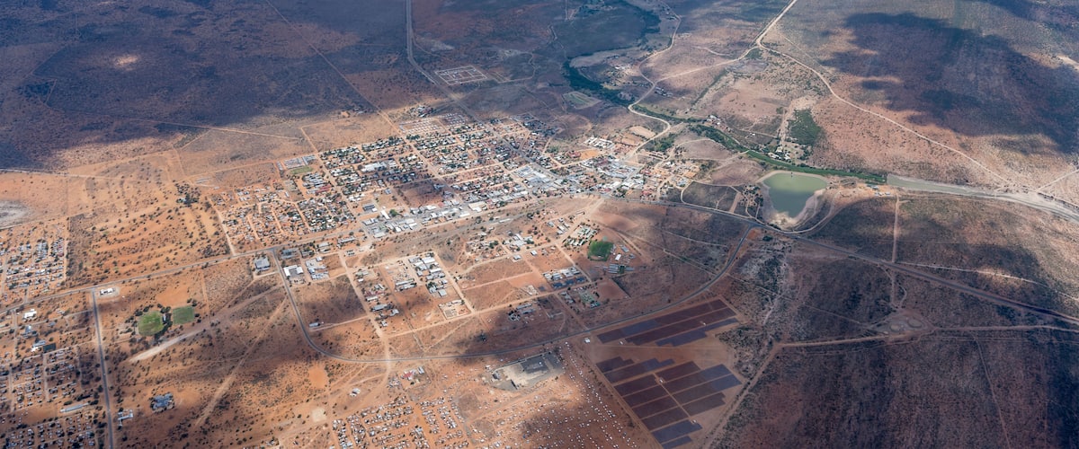 An aerial view of a town with a river, roads, and surrounding desert landscape.